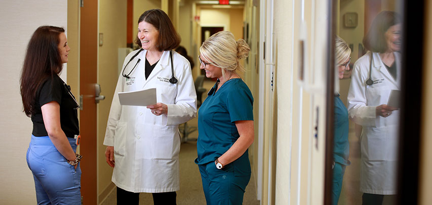 Dr. Susan Hulsemann chatting with two nurses in a hospital hallway.