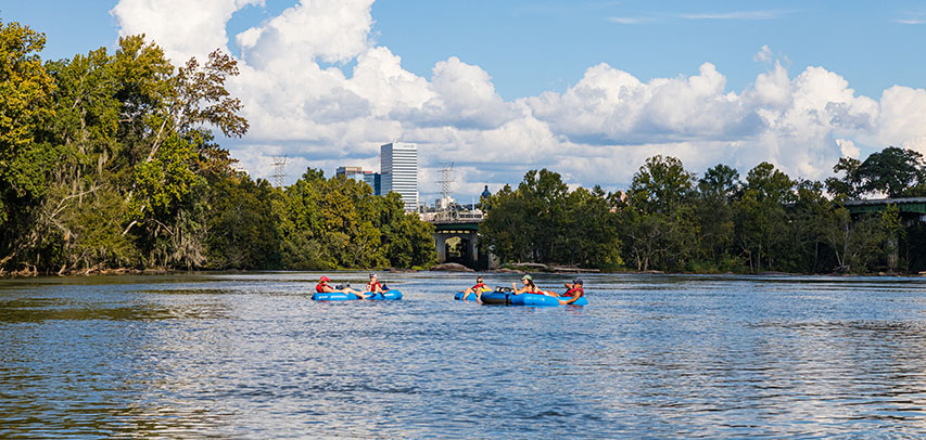 Locals tubing on the Saluda River with a view of downtown Columbia behind them.