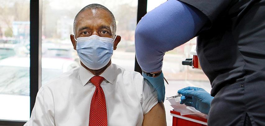 Reverend Jackson wearing a mask and getting vaccinated.