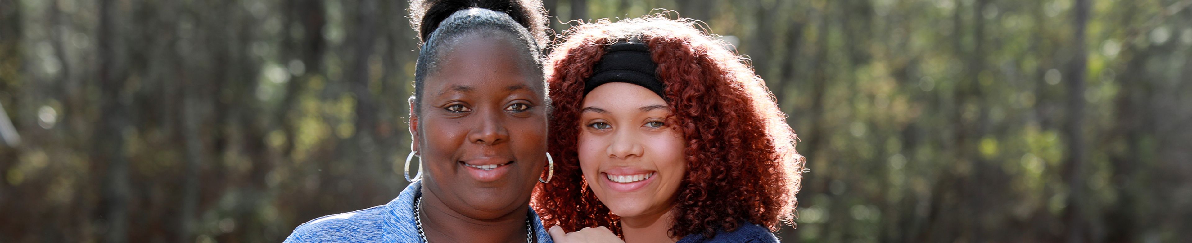 Mother and daughter outdoors on a beautiful day, smiling toward the camera.