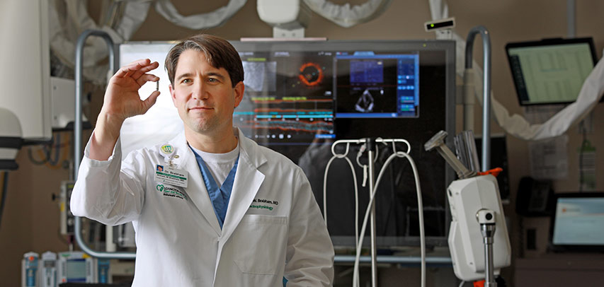 In the operating room, Dr. William Brabham shows off the Micra pacemaker, about the size of a vitamin pill, by holding it up between his thumb and index finger.