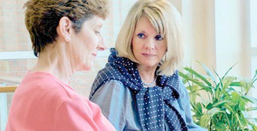 A Lexington Medical Center patient reads a brochure as a friend gives a supportive touch in a waiting area.