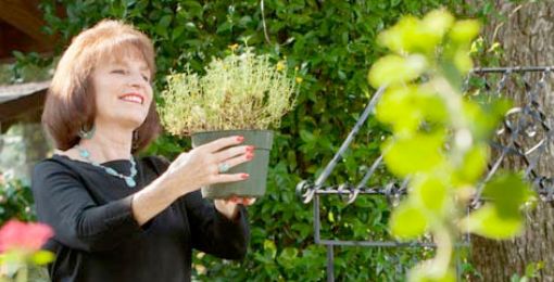 Lexington Medical Center patient Leslie Wyatt holds up a potted plant in her garden during a nice summer day.