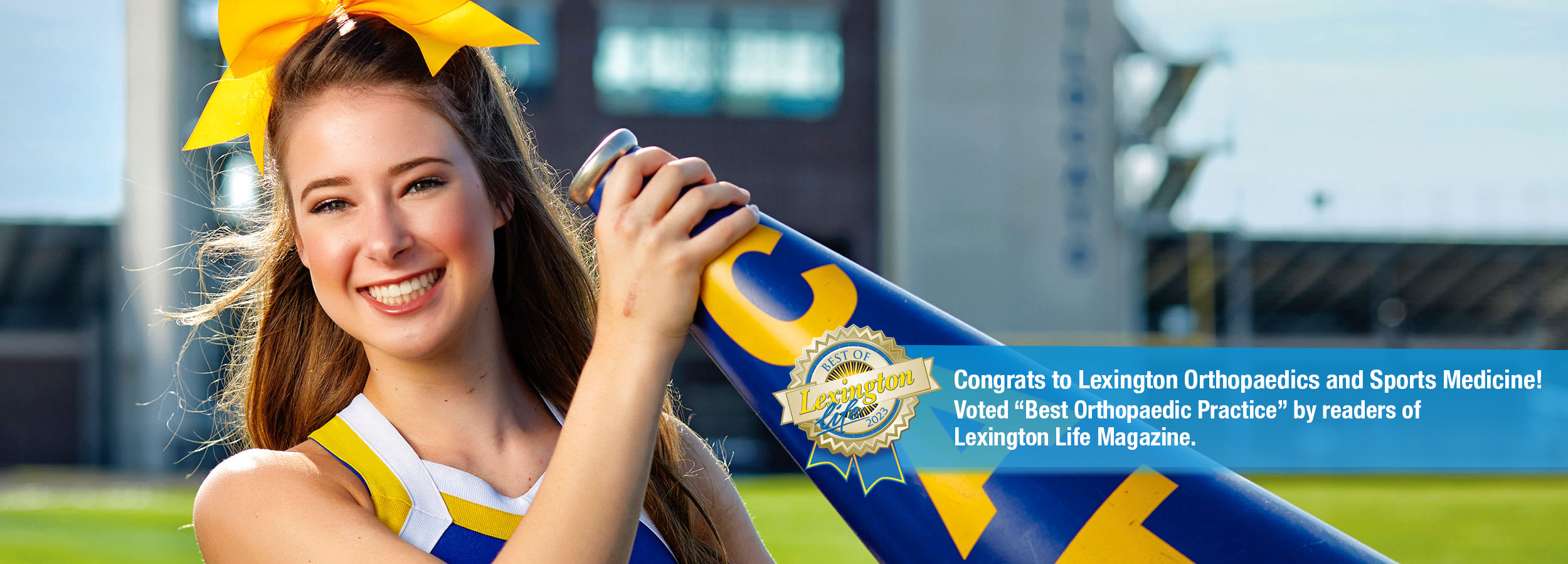 Hand injury patient Madison Kutyla in a cheer uniform holding up a megaphone on a football field.