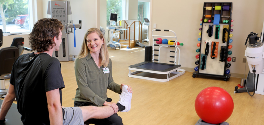 A physical therapist at a rehabilitation clinic holding a patient's foot and ankle.