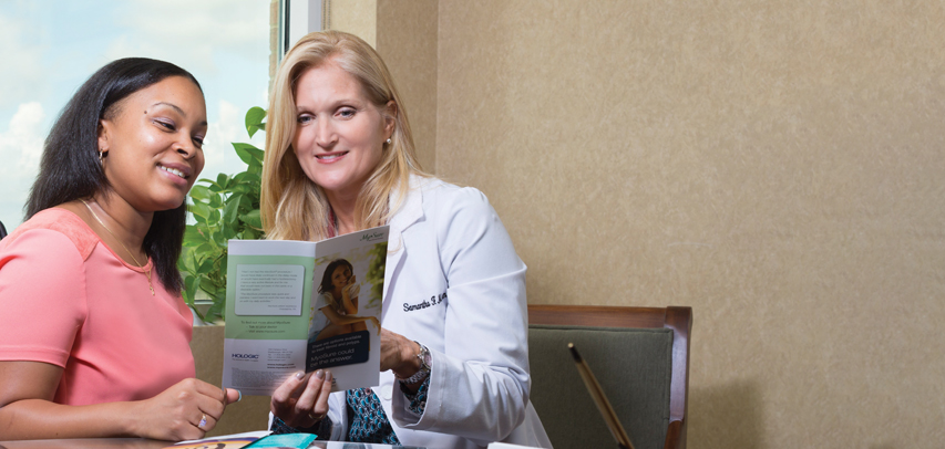 An LMC doctor and patient sitting in a warm doctor’s office, looking over paperwork together.