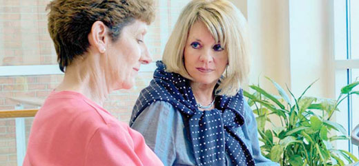A Lexington Medical Center patient reads a brochure as a friend gives a supportive touch in a waiting area.