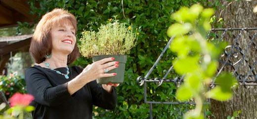 Lexington Medical Center patient Leslie Wyatt holds up a potted plant in her garden during a nice summer day.